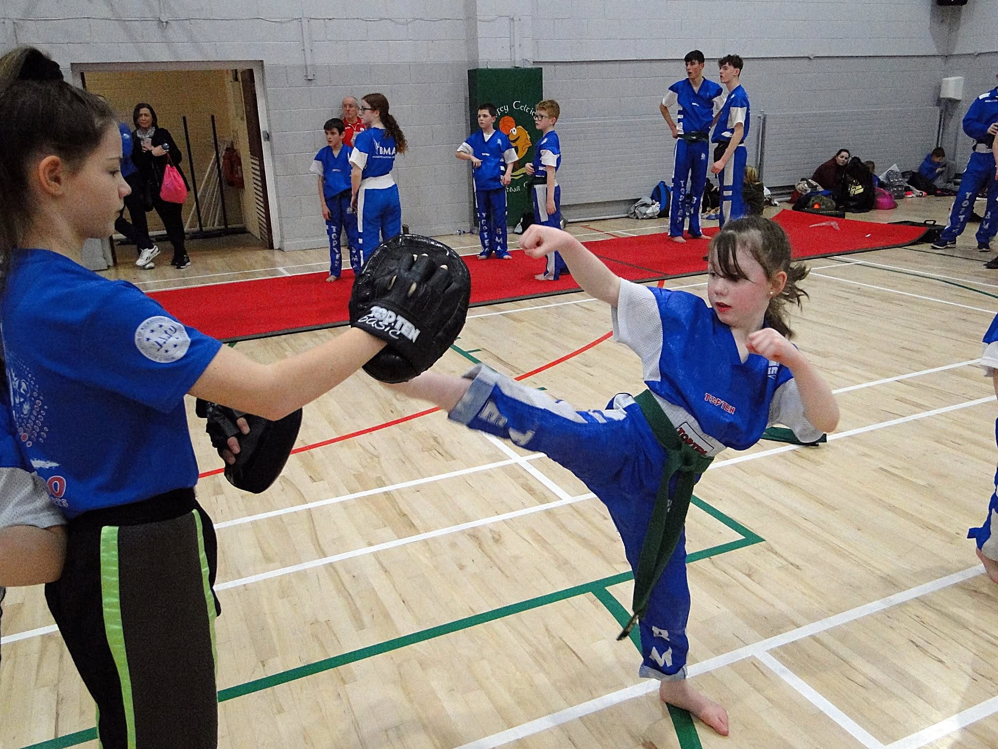 Bushido students practising kicks with a coach holding a pad